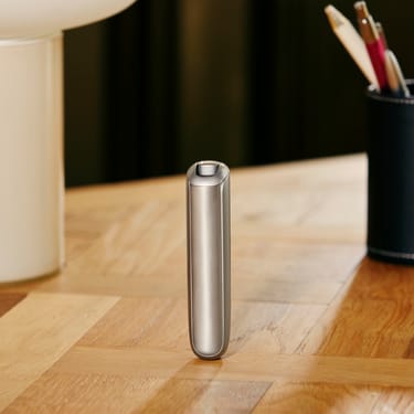 Man's hand turning a Ploom AURA Lunar Silver device on.
