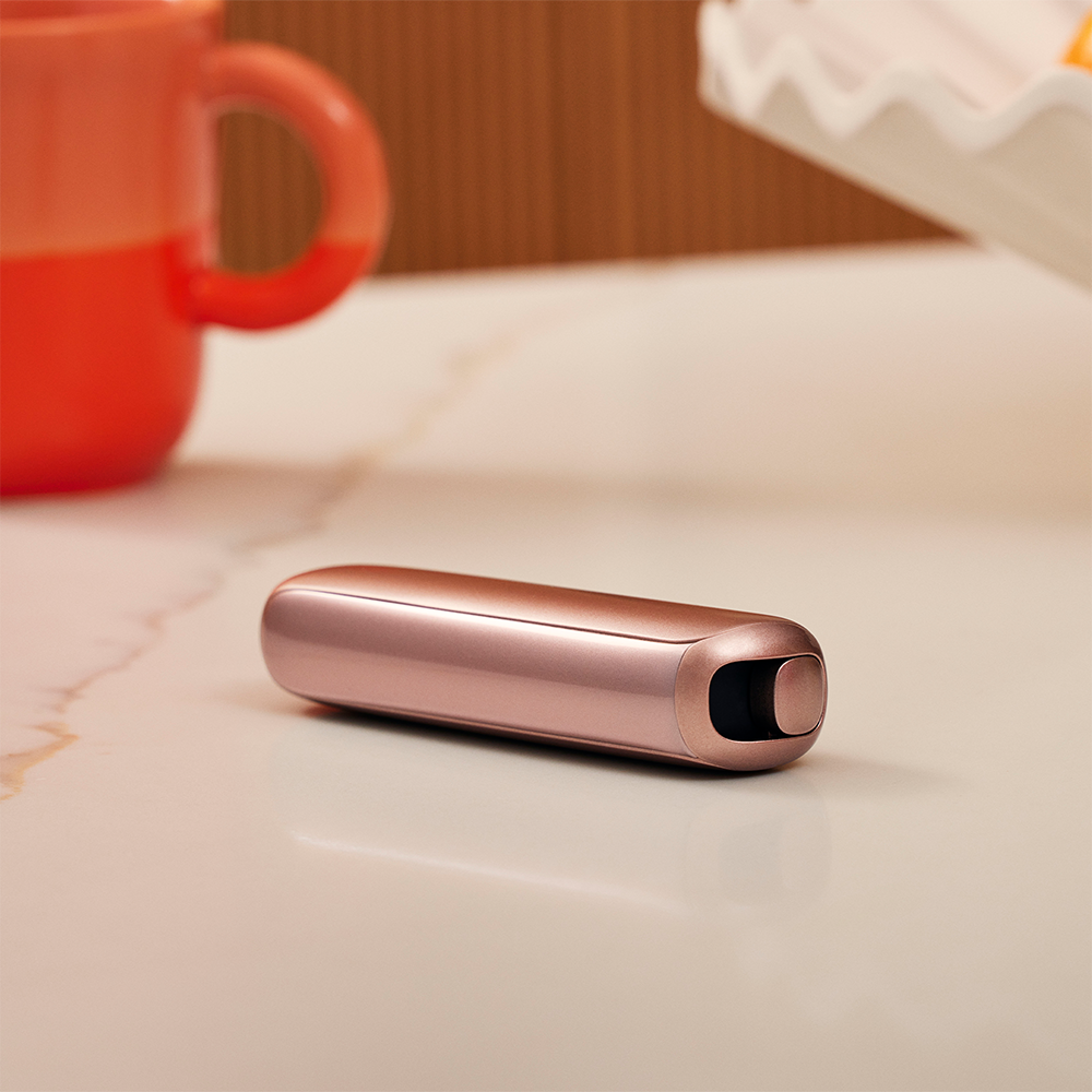Hand holding the Ploom AURA Rose Gold.