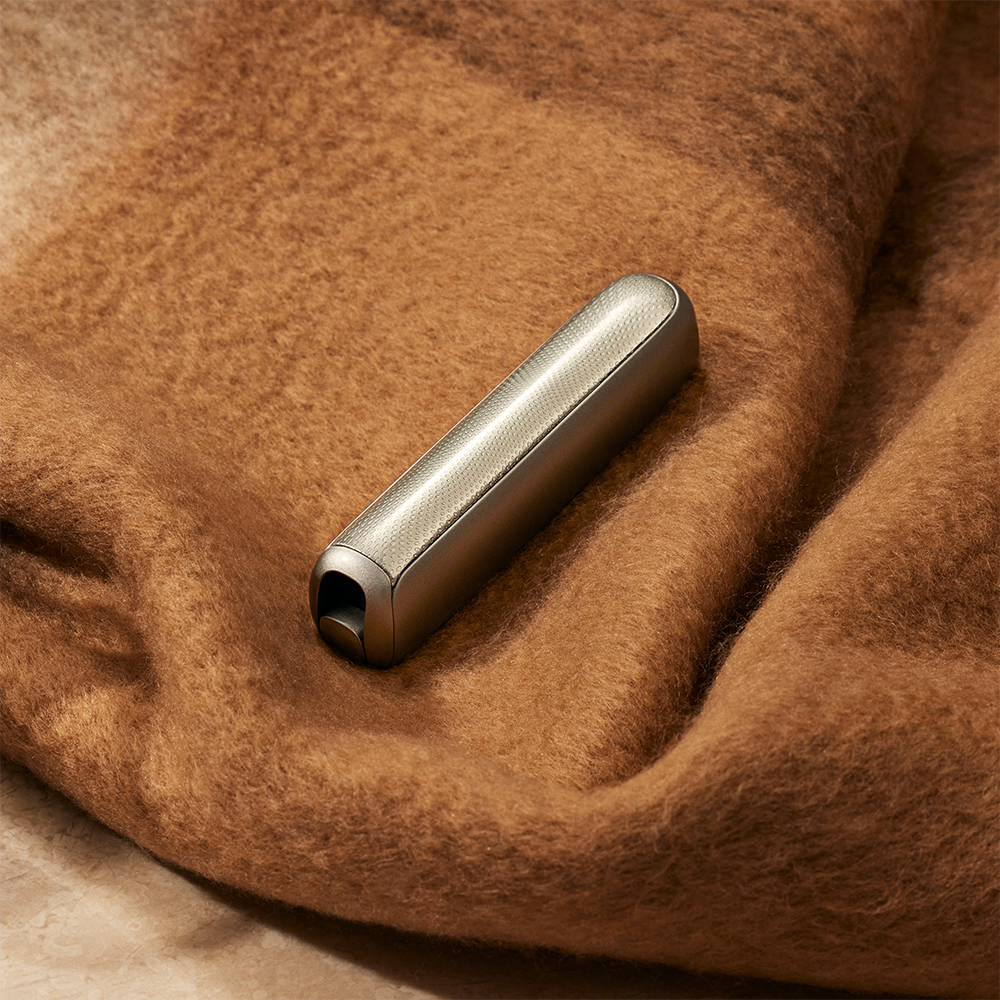 Ploom AURA with a Lunar Silver front panel placed on a maroon blanket