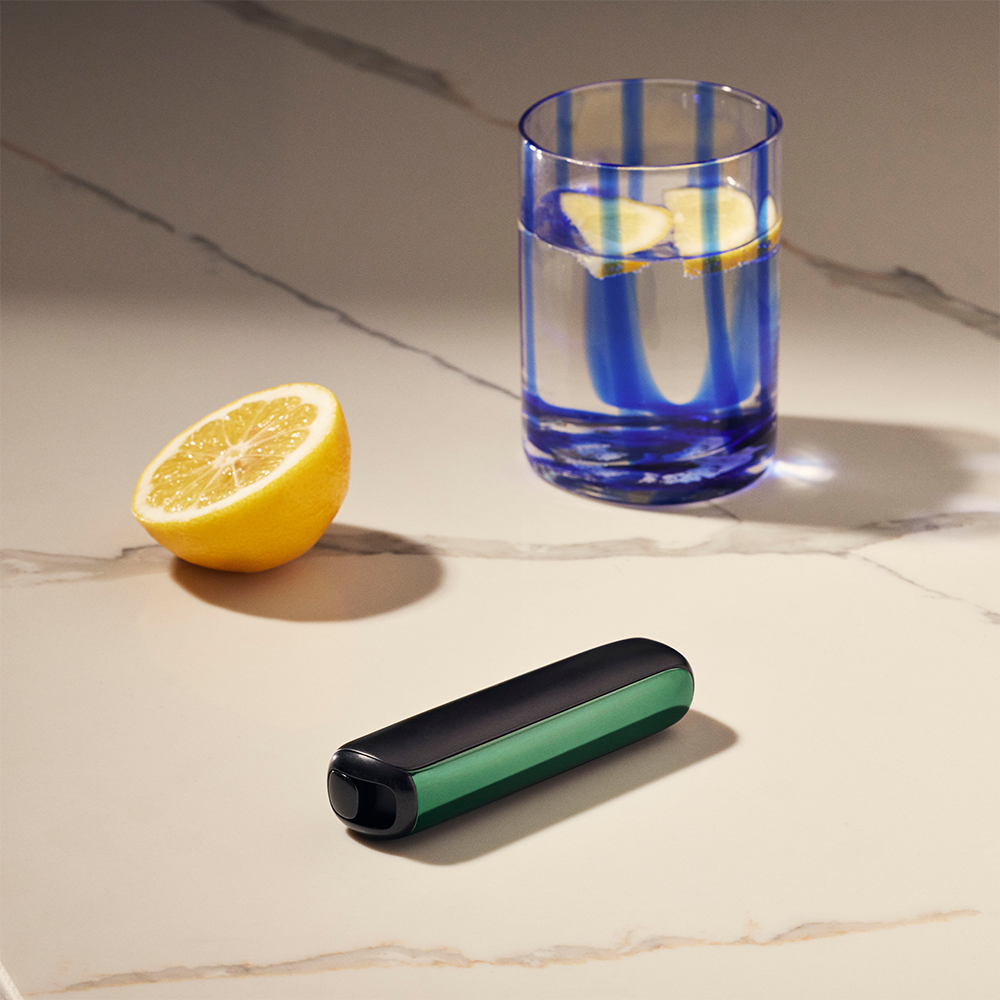 Ploom AURA front panel Amazon Green accessory attached to device on a table.