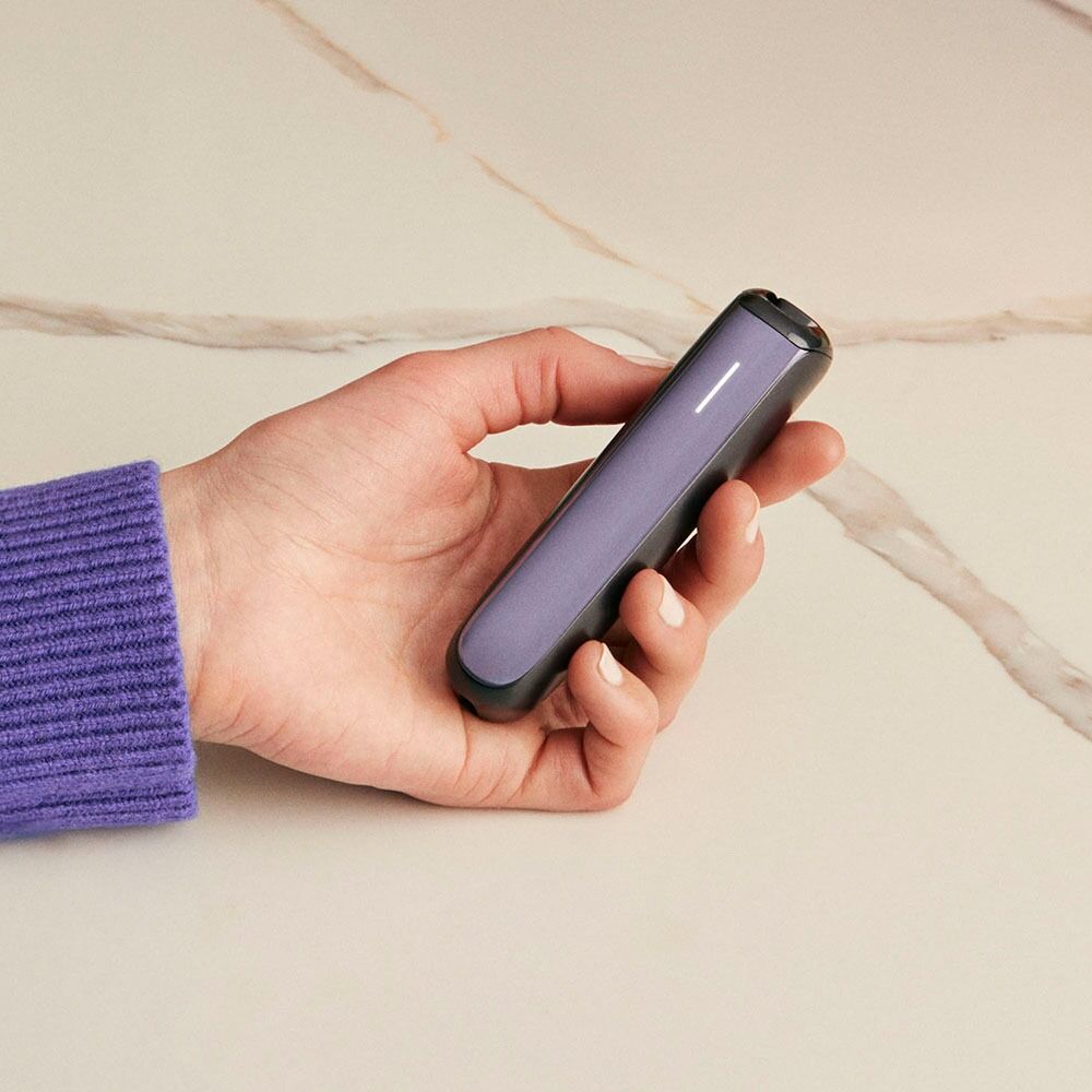 Hand holding Ploom AURA with Lavender front panel.