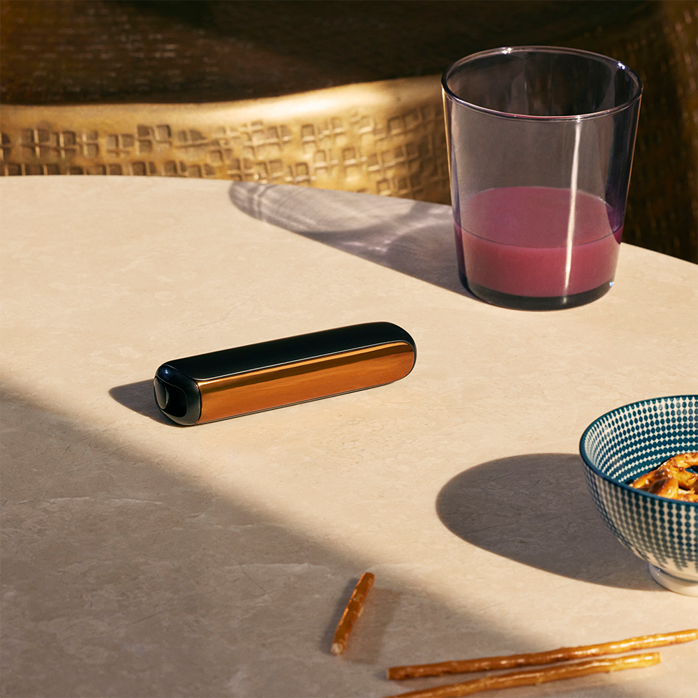 Ploom AURA front panel Mango Sorbet accessory attached to device on a table.