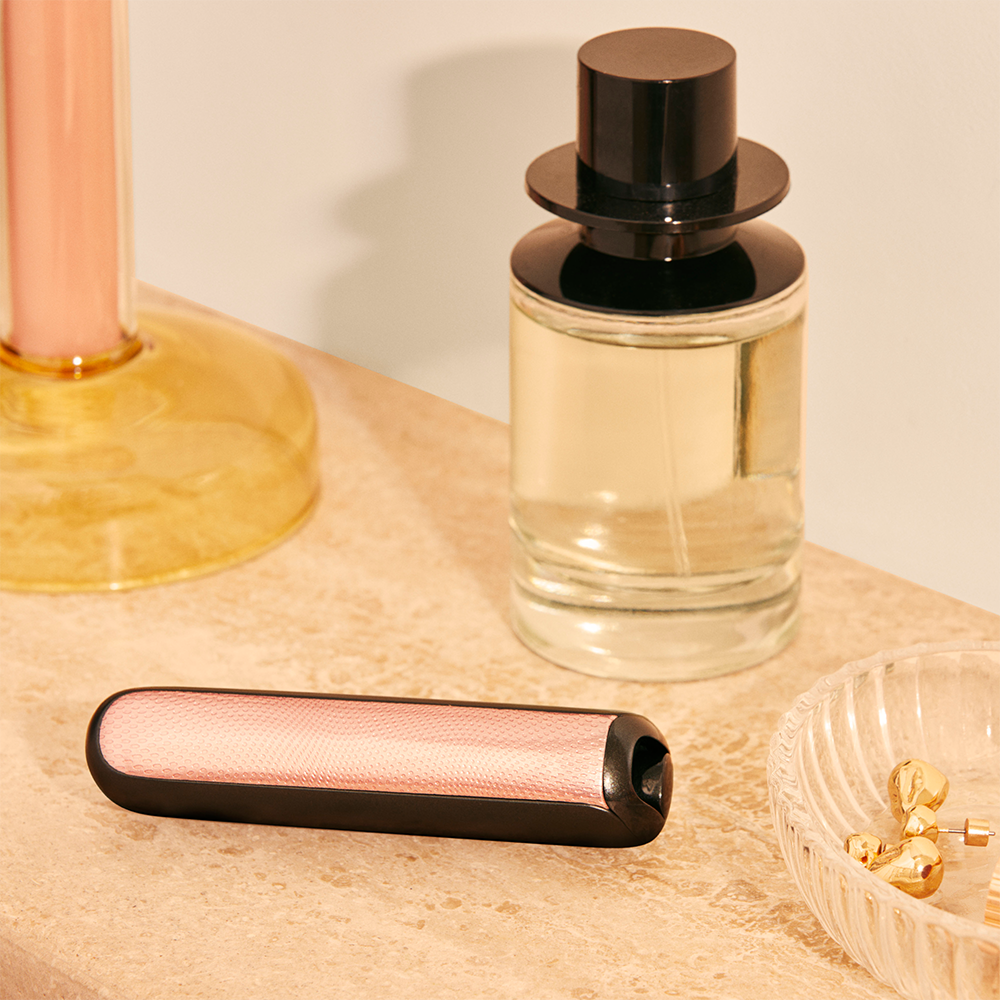 Ploom AURA front panels with Rose Gold Augmented Pattern placed on a dressing table.