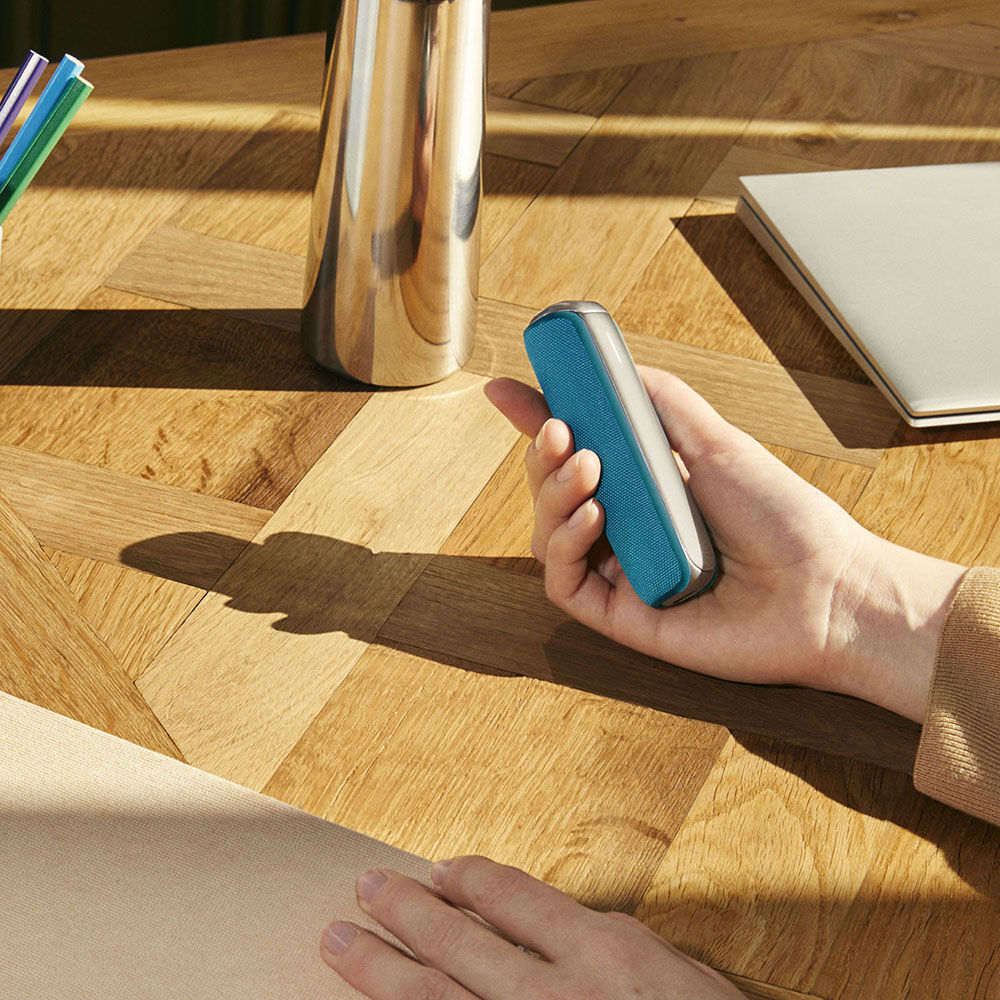 Hand Holding a Ploom AURA device with an Ocean Blue Back Cover accessory