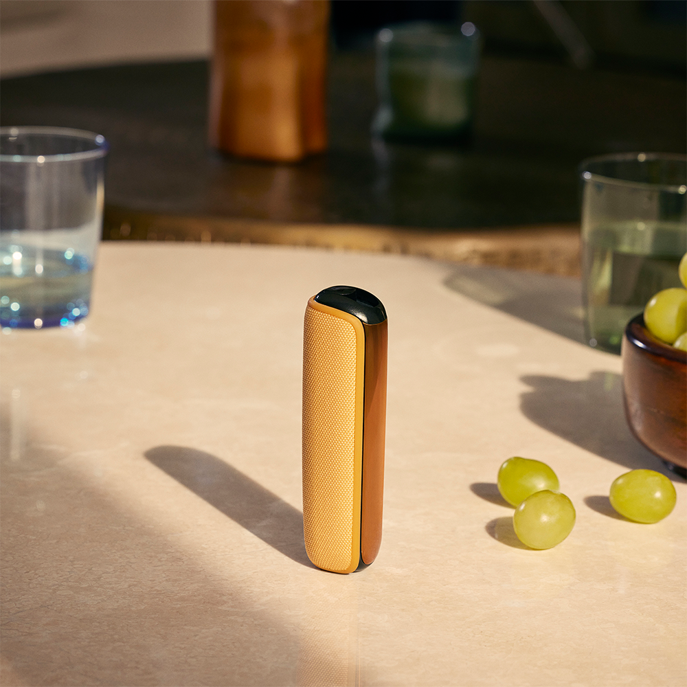 Ploom device with Mango Sorbet Back Cover standing on a table