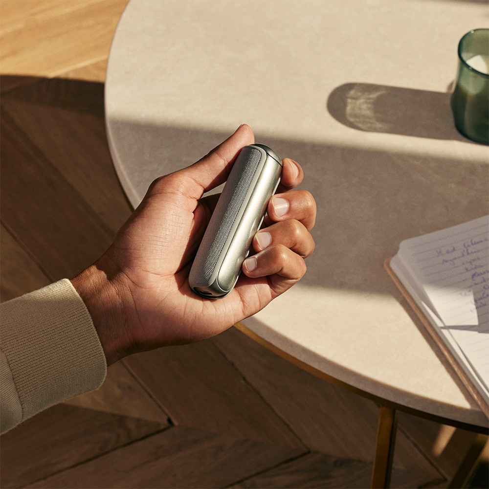 Hand holding Ploom AURA Back Cover Lunar Silver accessory on device.