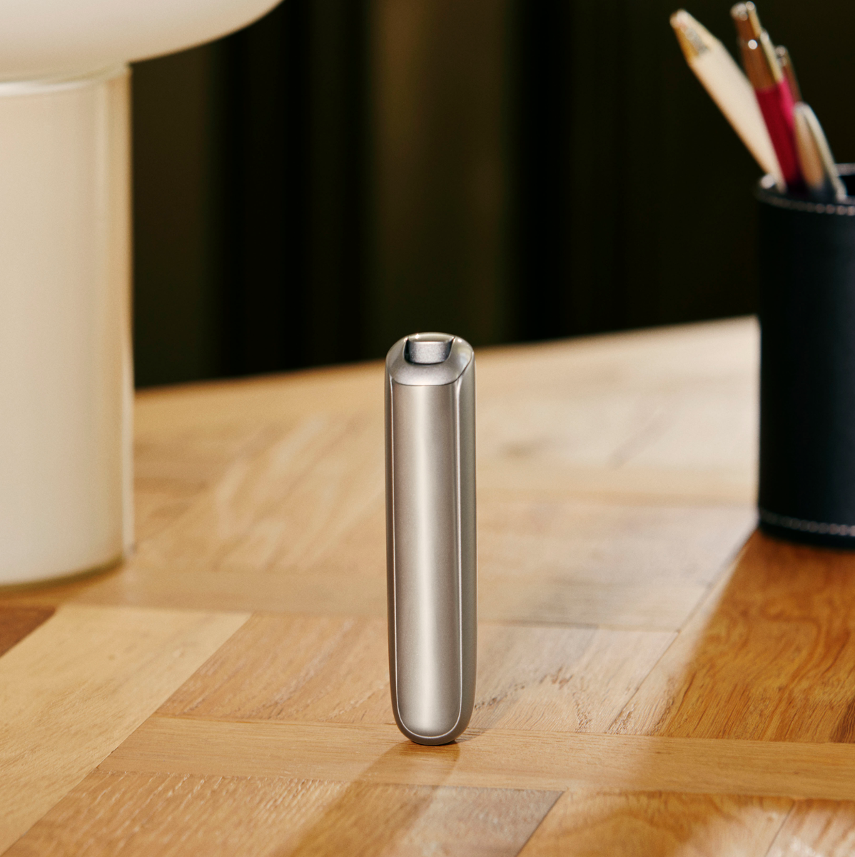 Man's hand turning a Ploom AURA Lunar Silver device on.